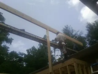 Carpenter setting a ridge beam over a new addition frame — Ice Dam Removal by Roofing Brothers in White Haven