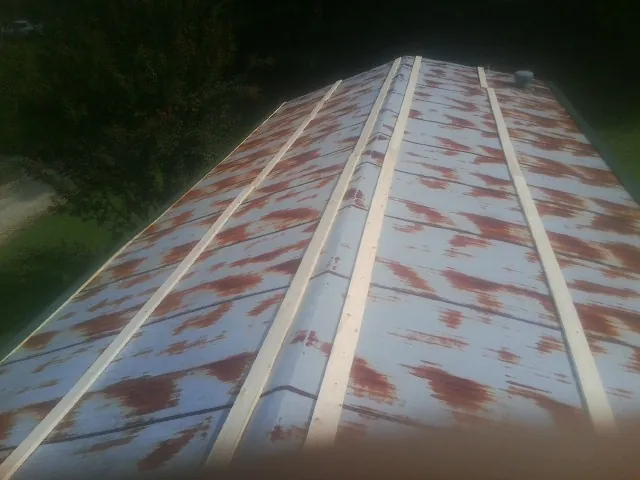 Rusted metal roof panels with new wood purlins before replacement — Storm Damage Roof Repair in White Haven by Roofing Brothers