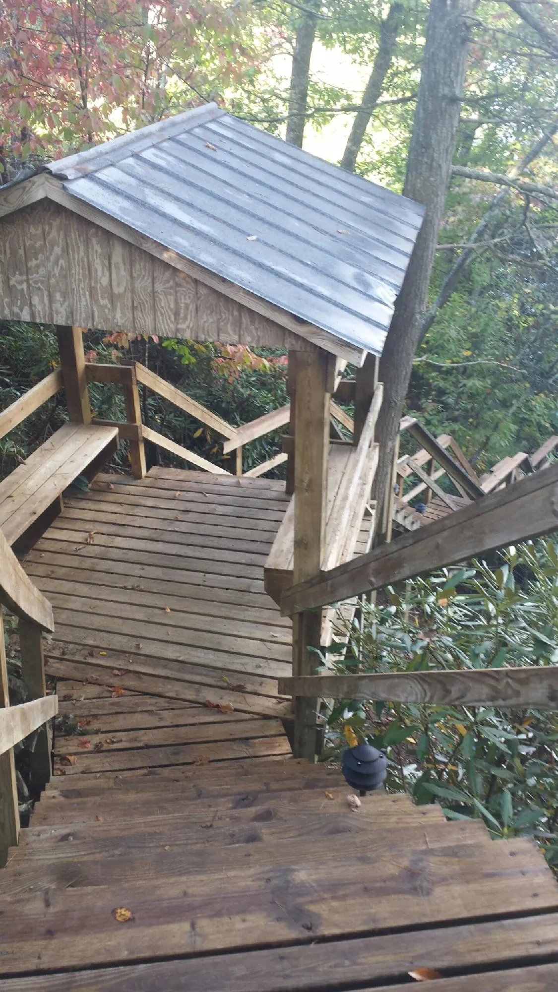 Metal roofed shelter over wooden steps on a wooded walkway — Skylight Repair & Installation work by our crew in White Haven