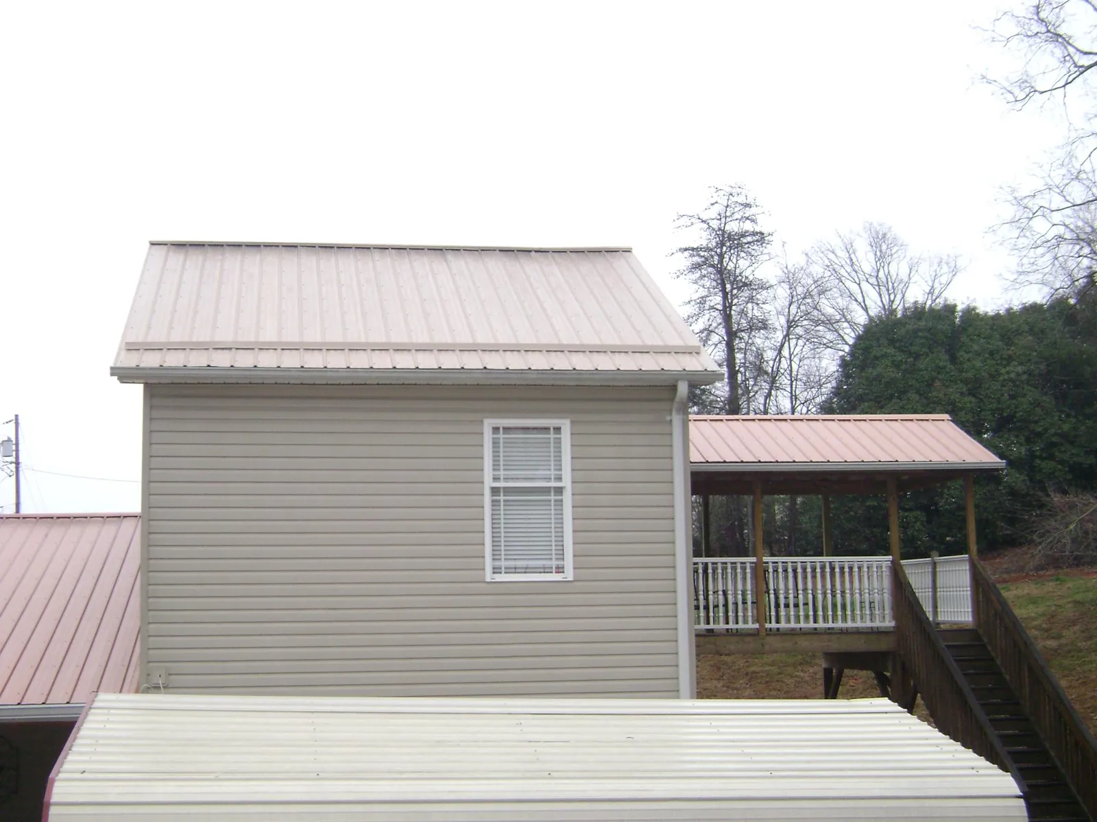 Tan metal roofs on a two story addition and attached porch, from a Roof Replacement job in White Haven