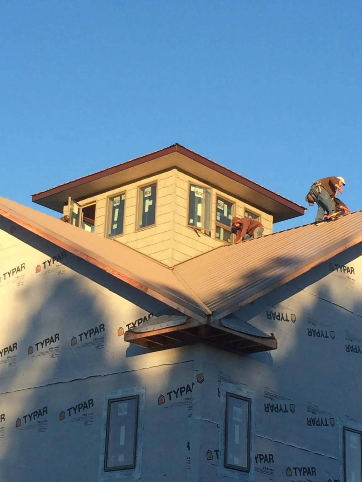 Roofers working around a rooftop cupola on a new metal roof at sunset — Roof Waterproofing in White Haven by Roofing Brothers